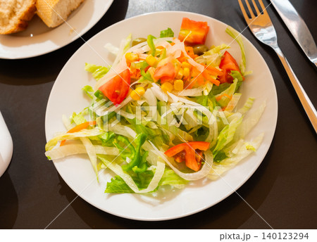 Plate contains portion of salad from fresh China cabbage, carrot, corn 140123294