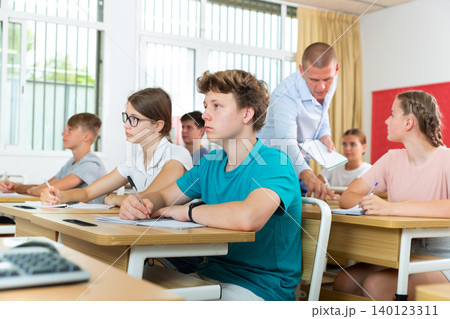 Focused teenage students studying in classroom with teacher 140123311