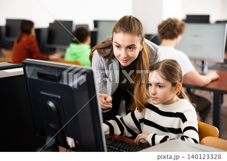 Female teacher helping teen schoolgirl studying in computer lab Female teacher helping teen schoolgirl studying in computer lab 140123328