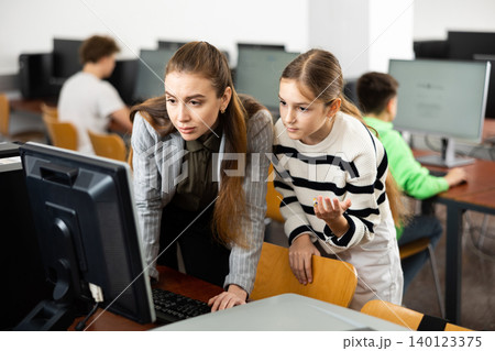 Female teacher and teenage girl looking at monitor of PC 140123375