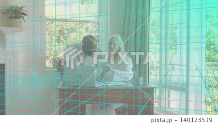 Reviewing couple in light shirts, pointing at laptop at dining nook with papers and teal grid Reviewing couple in light shirts, pointing at laptop at dining nook with papers and teal grid 140123519