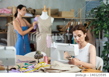 Woman tailor connects parts of dress on mannequin, female craftsman tailor work and sewing 140123595