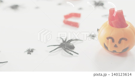 Showing orange jack-o'-lantern container sitting on table with black spiders, red candy, copy space Showing orange jack-o'-lantern container sitting on table with black spiders, red candy, copy space 140123614