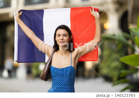 Girl waving France flag on street of summer city 140123765