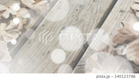 Showing weathered wooden planks running diagonally on porch surface, with dried leaves and bokeh Showing weathered wooden planks running diagonally on porch surface, with dried leaves and bokeh 140123786