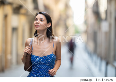Young woman looks around on city street 140123920