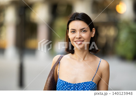 Young brunette girl in blue dress walking along the streets of the historical center of city 140123948