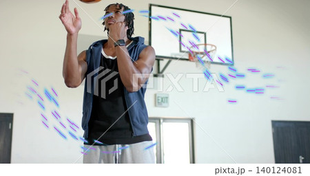 Tossing player wearing hoodie, sweats in gym with basketball, backboard, smartwatch, purple trails Tossing player wearing hoodie, sweats in gym with basketball, backboard, smartwatch, purple trails 140124081