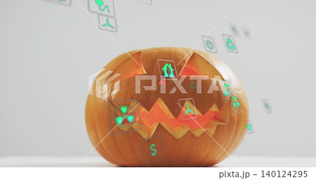 Sitting carved pumpkin glowing with internal light on tabletop, projecting green holographic icons Sitting carved pumpkin glowing with internal light on tabletop, projecting green holographic icons 140124295