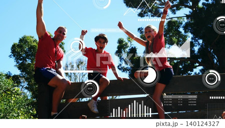 Cheering father and two children raising arms on wooden rail in park, wearing red shirts, overlays Cheering father and two children raising arms on wooden rail in park, wearing red shirts, overlays 140124327