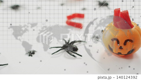 Showing pumpkin with red wrap sitting on grid backdrop, with two spiders, map overlay, copy space 140124392