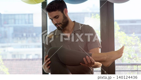 Cradling man in gray polo supporting leg at knee ankle, woman in dark leggings barefoot, windows Cradling man in gray polo supporting leg at knee ankle, woman in dark leggings barefoot, windows 140124436
