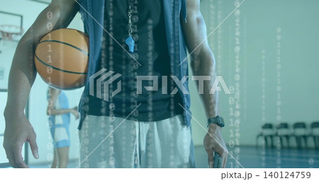 Holding coach's basketball and phone while standing on gym court, hoodie and binary overlay Holding coach's basketball and phone while standing on gym court, hoodie and binary overlay 140124759