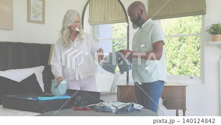 Packing woman in eyelet blouse and man in light shirt folding clothes in bedroom, with suitcase Packing woman in eyelet blouse and man in light shirt folding clothes in bedroom, with suitcase 140124842