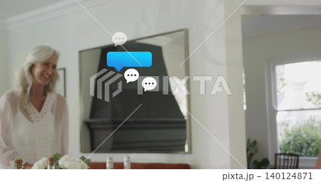 Smiling senior woman wearing white-blouse standing left of table, mirror, chat bubbles, copy space 140124871