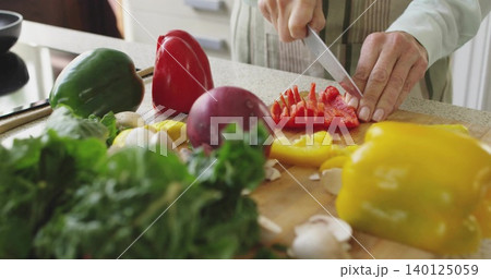 Slicing senior woman in striped apron cutting red pepper on wooden cutting board, copy space Slicing senior woman in striped apron cutting red pepper on wooden cutting board, copy space 140125059