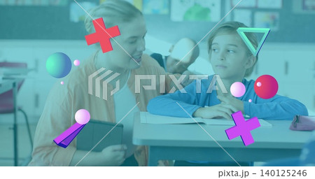 Kneeling teacher in peach cardigan guiding student in classroom holding tablet open workbook shapes Kneeling teacher in peach cardigan guiding student in classroom holding tablet open workbook shapes 140125246