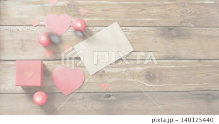 Displaying Valentine cluster on rustic wood table, with blank white card, pink hearts and gift box 140125440