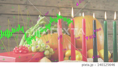 Showing festive centerpiece glowing with lit tapers and fruit on wooden tabletop chart overlay 140125646
