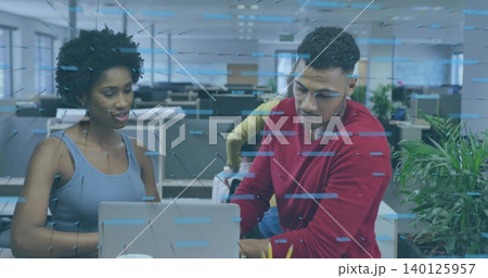 Collaborating two coworkers wearing gray top and red sweater leaning over laptop at office, cup 140125957