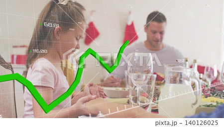 Praying girl at left in pink T-shirt sitting at home dining table, green graph overlay 140126025