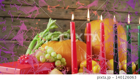 Displaying centered autumnal centerpiece on wood table with lit taper candles, pumpkin, red gift Displaying centered autumnal centerpiece on wood table with lit taper candles, pumpkin, red gift 140126063
