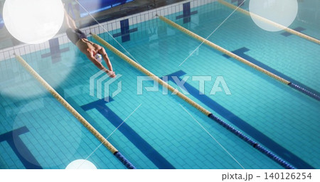 Diving male swimmer into competition lane in pool, in cap, dark briefs, lane ropes, copy space Diving male swimmer into competition lane in pool, in cap, dark briefs, lane ropes, copy space 140126254