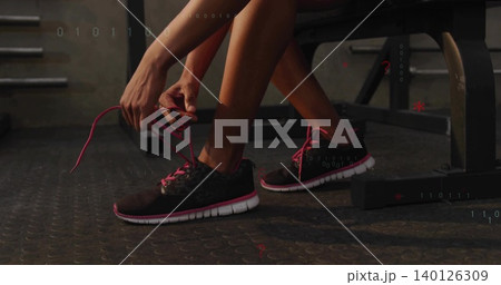 Tying woman wearing athletic shorts securing bright pink shoelaces on gym weight bench, rubber mat Tying woman wearing athletic shorts securing bright pink shoelaces on gym weight bench, rubber mat 140126309
