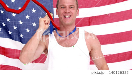 Holding blue-ribbon medal at mouth, smiling man wearing white-tee by US flag with red decline grid Holding blue-ribbon medal at mouth, smiling man wearing white-tee by US flag with red decline grid 140126325