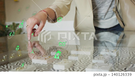 Leaning woman in beige blazer reaching ring on glass display at boutique with green AR icons Leaning woman in beige blazer reaching ring on glass display at boutique with green AR icons 140126339