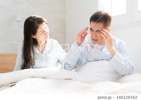 起きてベッドの上で会話をする夫婦 起きてベッドの上で会話をする夫婦 140126502