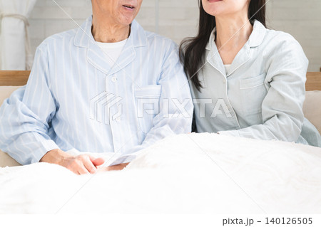 起きてベッドの上で会話をする夫婦 起きてベッドの上で会話をする夫婦 140126505