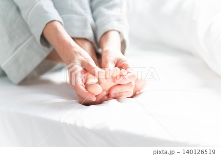 起きてベッドの上で足が攣る女性 起きてベッドの上で足が攣る女性 140126519