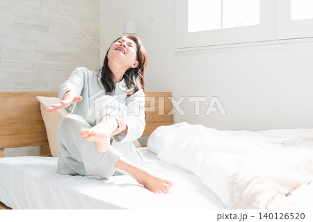 起きてベッドの上で足が攣る女性 起きてベッドの上で足が攣る女性 140126520