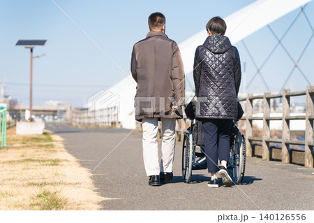 車椅子を押して散策をする親子 車椅子を押して散策をする親子 140126556