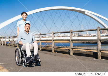 車椅子を押して散策する男性と介護士 車椅子を押して散策する男性と介護士 140126564