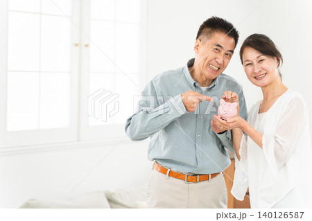 豚の貯金箱を持つ熟年夫婦 豚の貯金箱を持つ熟年夫婦 140126587