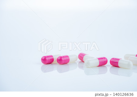 Pink-white antibiotic capsules spread on white background. Prescription drug. Antibiotic resistance in modern medicine. Healthcare and pharmaceutical industry. Medical care, pharmaceutical research. 140126636