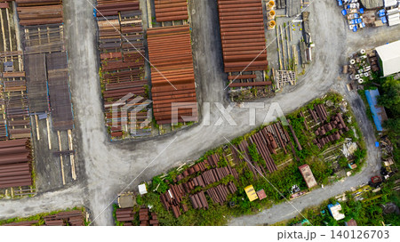 Aerial view of industrial steel pipe yard. Rusted and new construction materials. Infrastructure supply, recycling potential, and urban storage logistics. Sustainable infrastructure management. Aerial view of industrial steel pipe yard. Rusted and new construction materials. Infrastructure supply, recycling potential, and urban storage logistics. Sustainable infrastructure management. 140126703