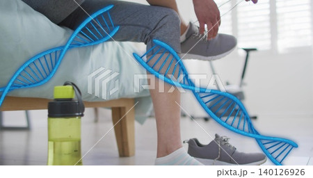 Tying woman wearing gray leggings lacing gray shoe in bedroom, with lime green bottle, bike, DNA Tying woman wearing gray leggings lacing gray shoe in bedroom, with lime green bottle, bike, DNA 140126926
