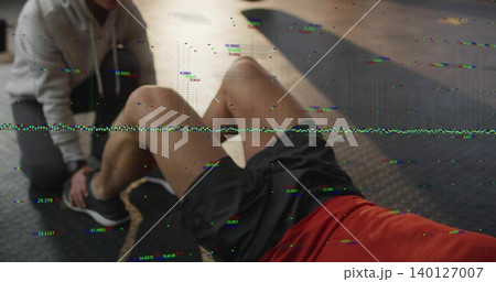 Performing man doing situps on gym mat in red tee, partner bracing feet, battle rope, glitch 140127007