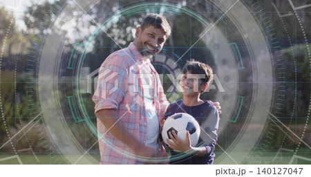 Standing father putting arm around son on grass, wearing pink shirt, holding soccer ball with HUD 140127047