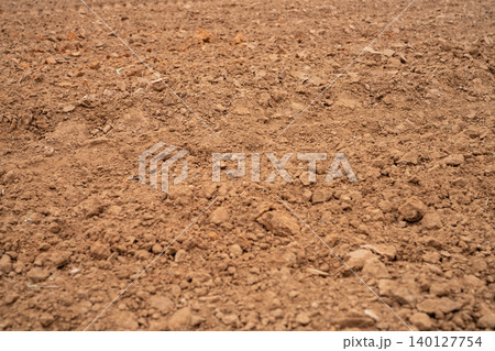 Agricultural field with plowed dirt after harvest season. Rural farming landscape prepared for planting crops to support sustainable agriculture and healthy soil ecosystem. Plowed agricultural soil. Agricultural field with plowed dirt after harvest season. Rural farming landscape prepared for planting crops to support sustainable agriculture and healthy soil ecosystem. Plowed agricultural soil. 140127754