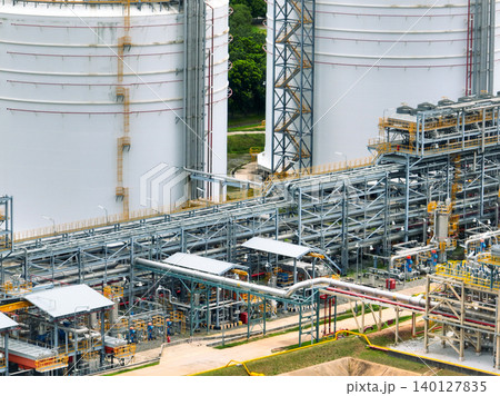 Industrial oil refinery with complex network of steel pipelines and massive storage tanks. Petrochemical plant producing fuel energy. Modern industrial infrastructure for petroleum processing. 140127835