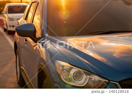 Luxury SUV with modern design parked on roadside at sunset. Front view of blue vehicle, symbolizing business success and eco-friendly technology. Electric vehicle. Sustainable travel. Summer road trip 140128018