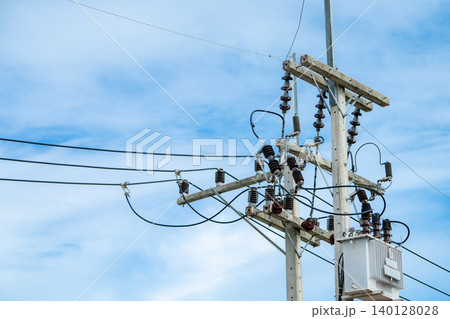 Electrical utility pole equipment featuring power transmission cables and insulators against blue sky demonstrating energy infrastructure technology for renewable wind farm power distribution 140128028