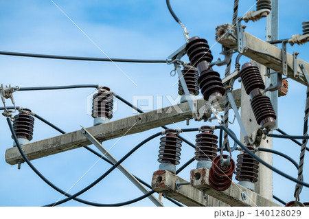 High voltage transmission pole with electrical equipment including cables and insulators on concrete structure under clear blue sky showing modern power grid infrastructure in wind energy facility 140128029
