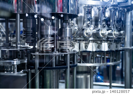 Automated stainless steel filling machine in factory. Precision nozzles and mechanical components. Beverage and pharmaceutical production, hygiene control, and industrial manufacturing efficiency. Automated stainless steel filling machine in factory. Precision nozzles and mechanical components. Beverage and pharmaceutical production, hygiene control, and industrial manufacturing efficiency. 140128057
