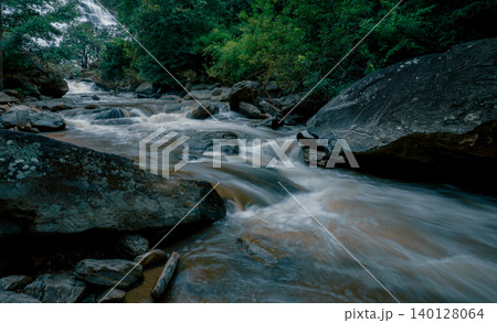 Beautiful waterfall with a lush green forest in the background. The water is flowing down the rocks and creating a beautiful scene. Sustainable waterfall in lush forest promoting water sustainability. 140128064