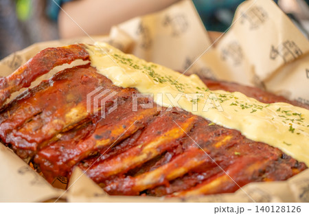 A rack of ribs with a creamy sauce on top. The ribs are cooked and appear to be very tender. The sauce is a creamy white sauce that complements the meat well. Concept of indulgence and satisfaction A rack of ribs with a creamy sauce on top. The ribs are cooked and appear to be very tender. The sauce is a creamy white sauce that complements the meat well. Concept of indulgence and satisfaction 140128126